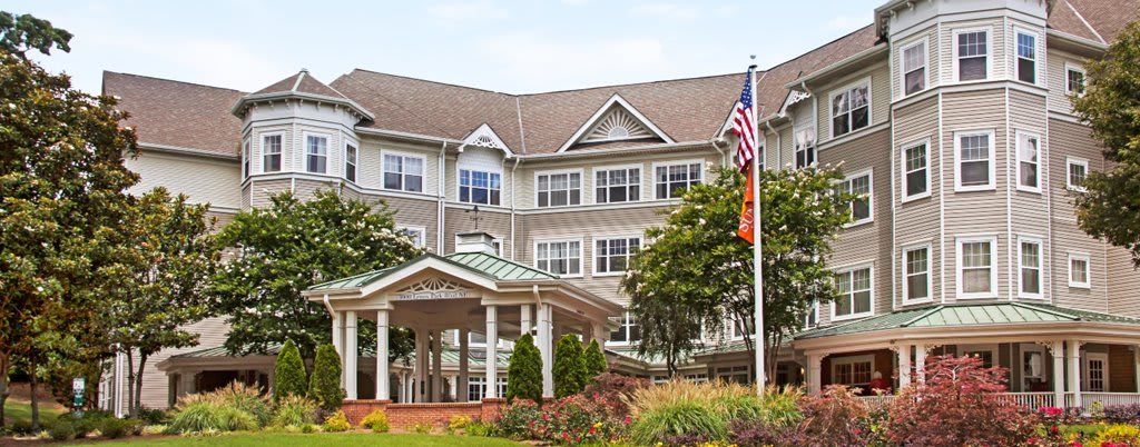 A large residential building with a landscaped entrance and flagpoles.