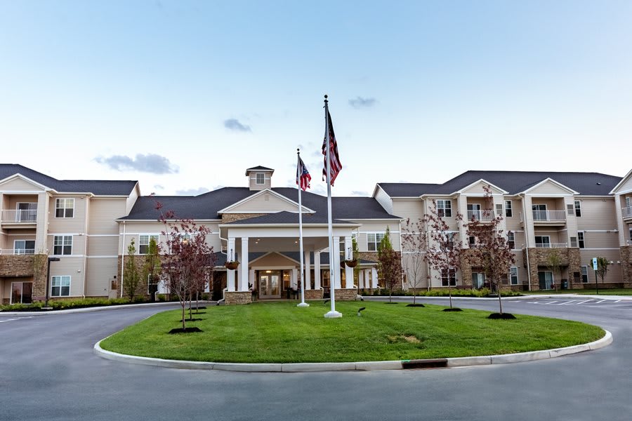 A large building with an elegant entrance, featuring flags and a well-maintained lawn in front.