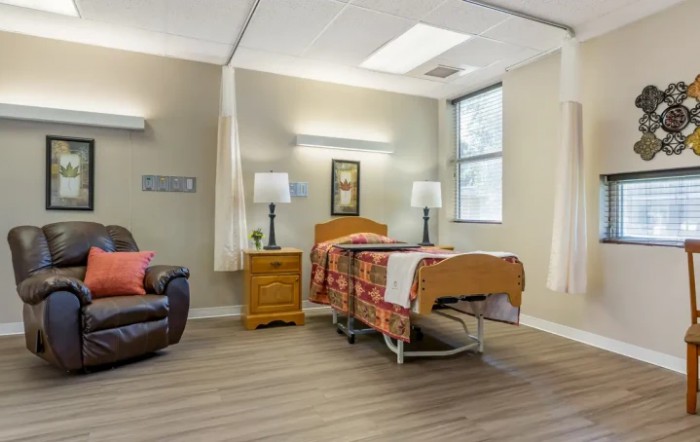 A well-lit hospital room featuring a bed, comfortable seating, and various furnishings.