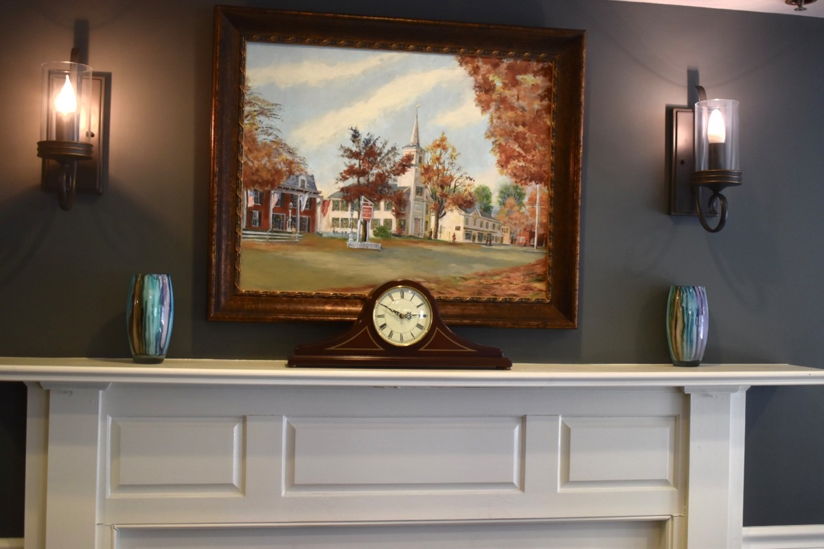 A classic mantel display with a landscape painting and a vintage clock.
