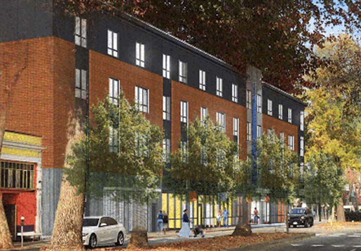 A modern multi-story building with trees lining the street and parked cars.