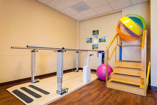 A well-equipped rehabilitation area featuring a balance bar, exercise balls, and stairs for physical therapy.
