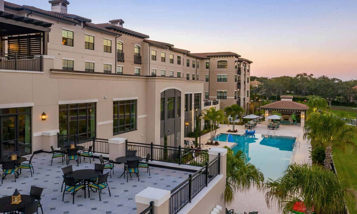 A modern hotel with a beautiful pool area and outdoor seating at sunset.