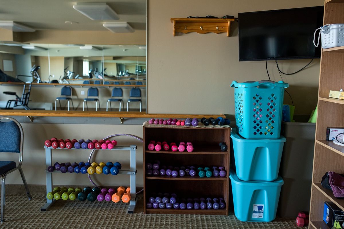 A fitness room with organized dumbbells and storage bins.