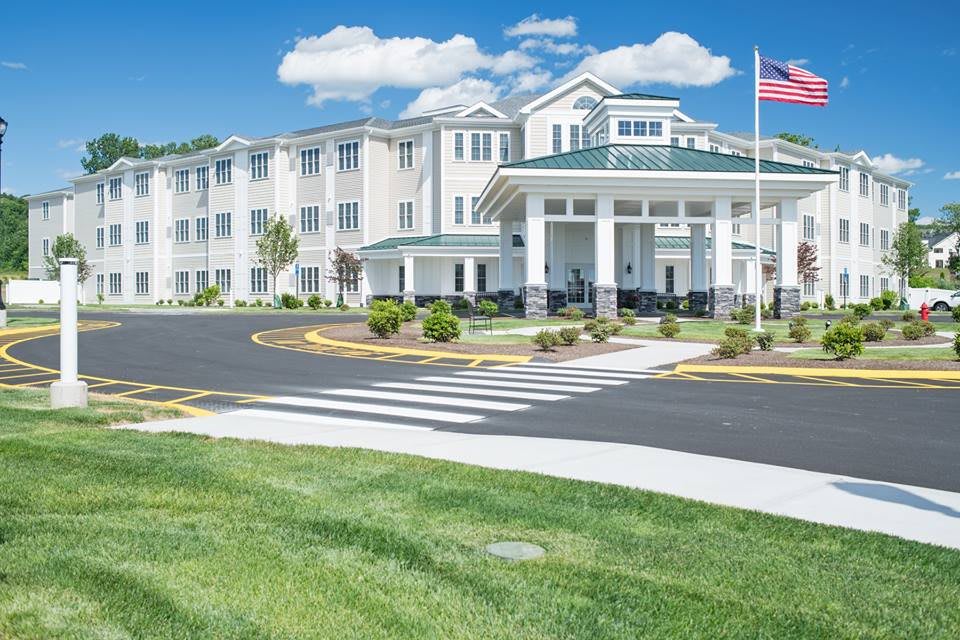 A well-maintained hotel or residential building with a landscaped entrance and an American flag.