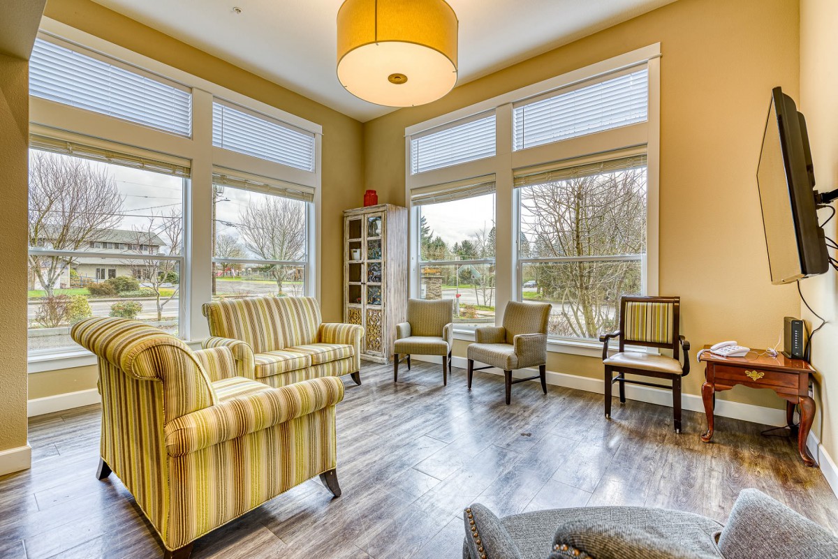A cozy living room with striped armchairs and large windows letting in natural light.