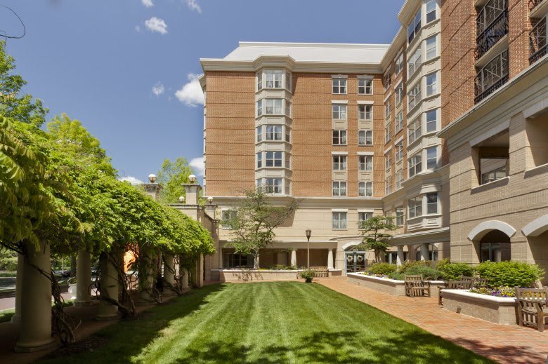 A well-maintained garden area in front of a multi-story brick building under a clear blue sky.