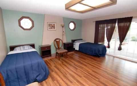 A spacious bedroom with two single beds and wood flooring.