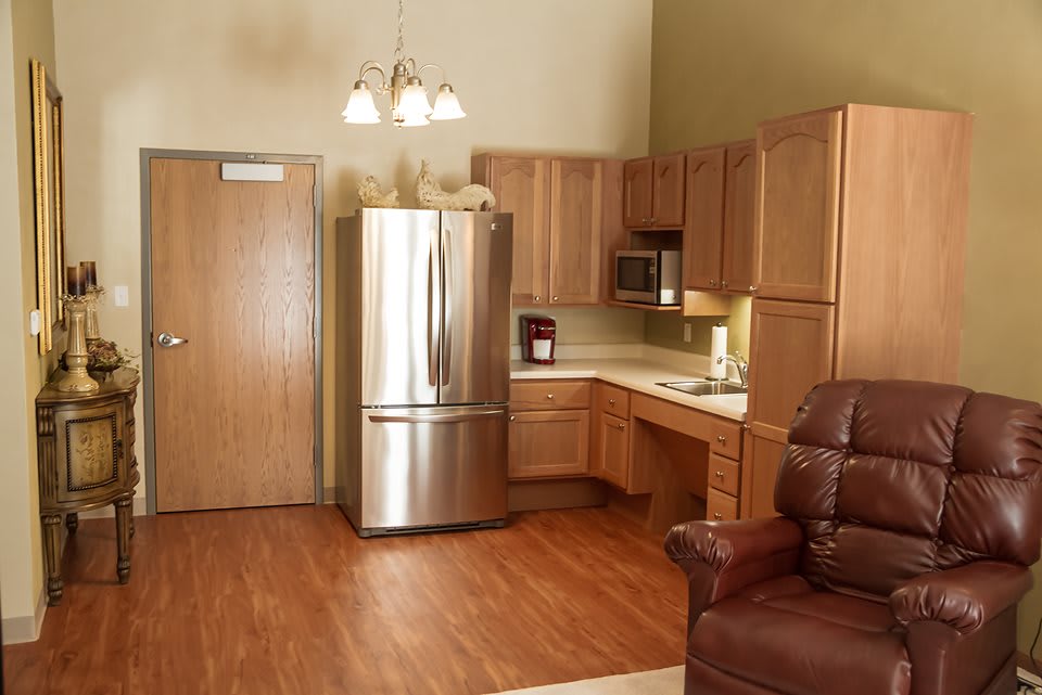A modern kitchen with wooden cabinets, a stainless steel refrigerator, and microwave.