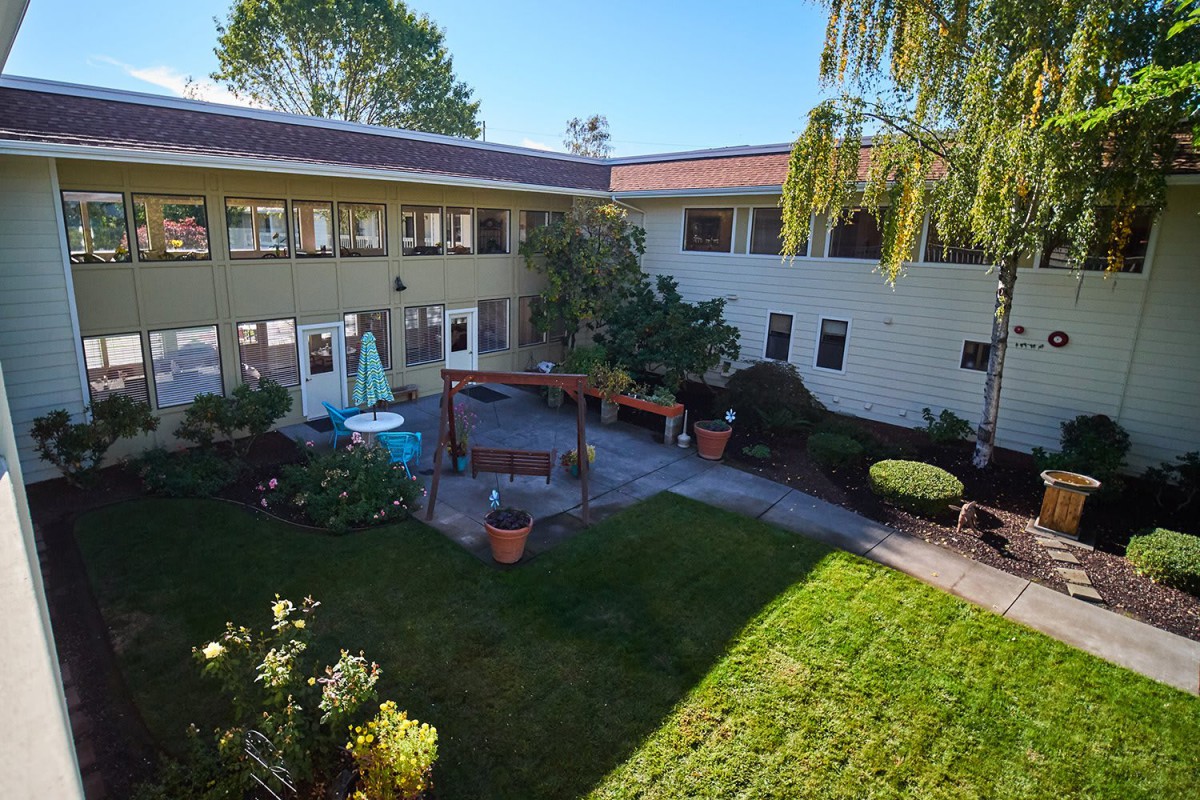 A sunny courtyard surrounded by a building with a garden area.