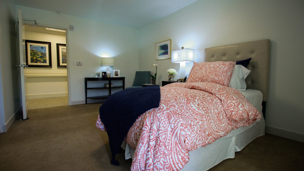 A cozy bedroom with a patterned bedspread, side tables with lamps, and a comfortable chair.