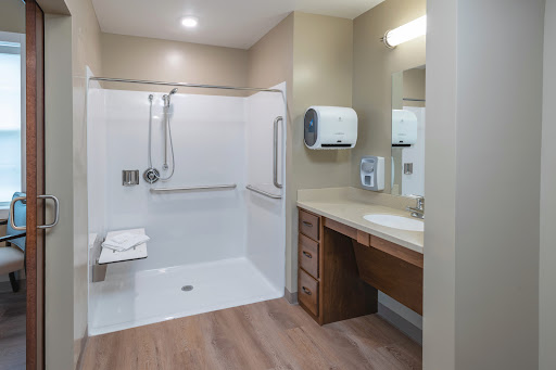 A spacious and modern bathroom designed for accessibility, featuring a shower area and a wooden vanity.