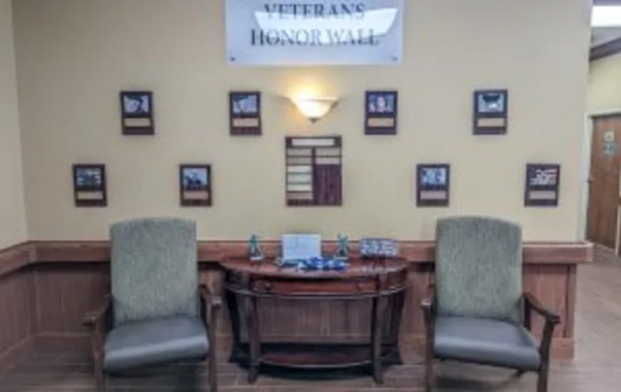 An honor wall dedicated to veterans, featuring a central desk and surrounded by chairs and commemorative plaques.