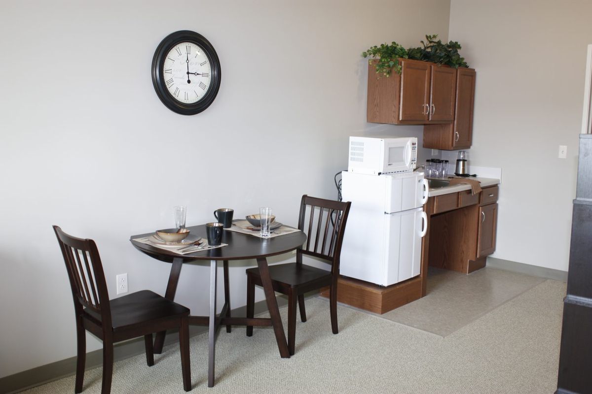 A small kitchen and dining area with a table, chairs, microwave, and refrigerator.
