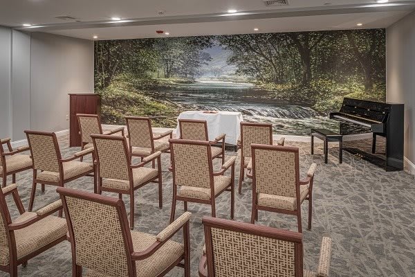 A small conference room with arranged chairs facing a mural of a serene landscape.