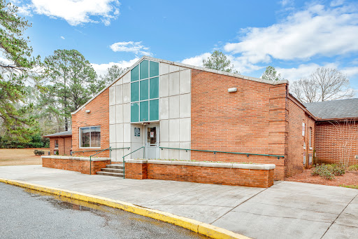 A modern brick building featuring a distinctive angular design and surrounded by a bright blue sky.