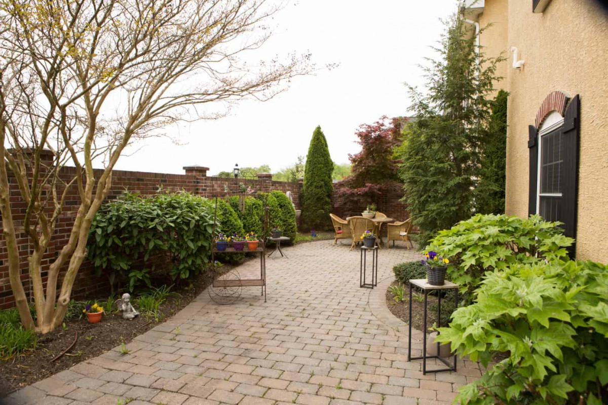 A beautifully landscaped garden with a paved patio and outdoor furniture.
