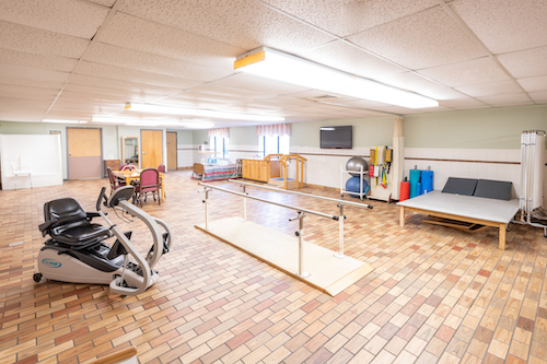 A spacious rehabilitation center equipped with exercise machines, walking bars, and a comfortable environment for physical therapy.