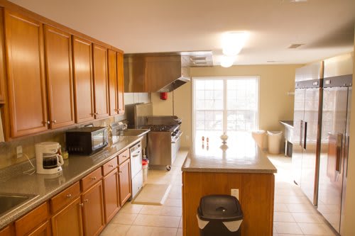 A modern kitchen with wooden cabinets and an island, equipped with appliances.
