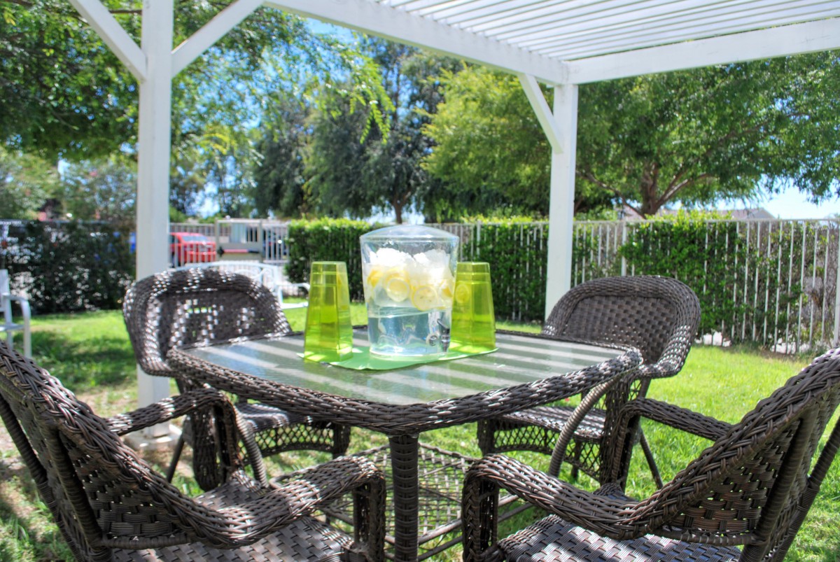 A sunny outdoor patio with wicker furniture and a table set for refreshments.