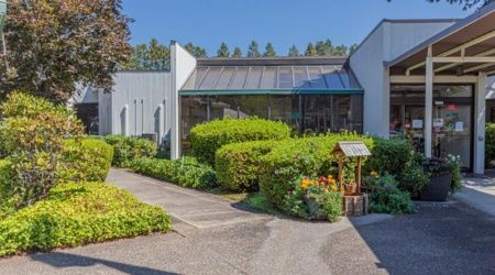 A modern building entrance surrounded by neatly landscaped gardens and pathways.