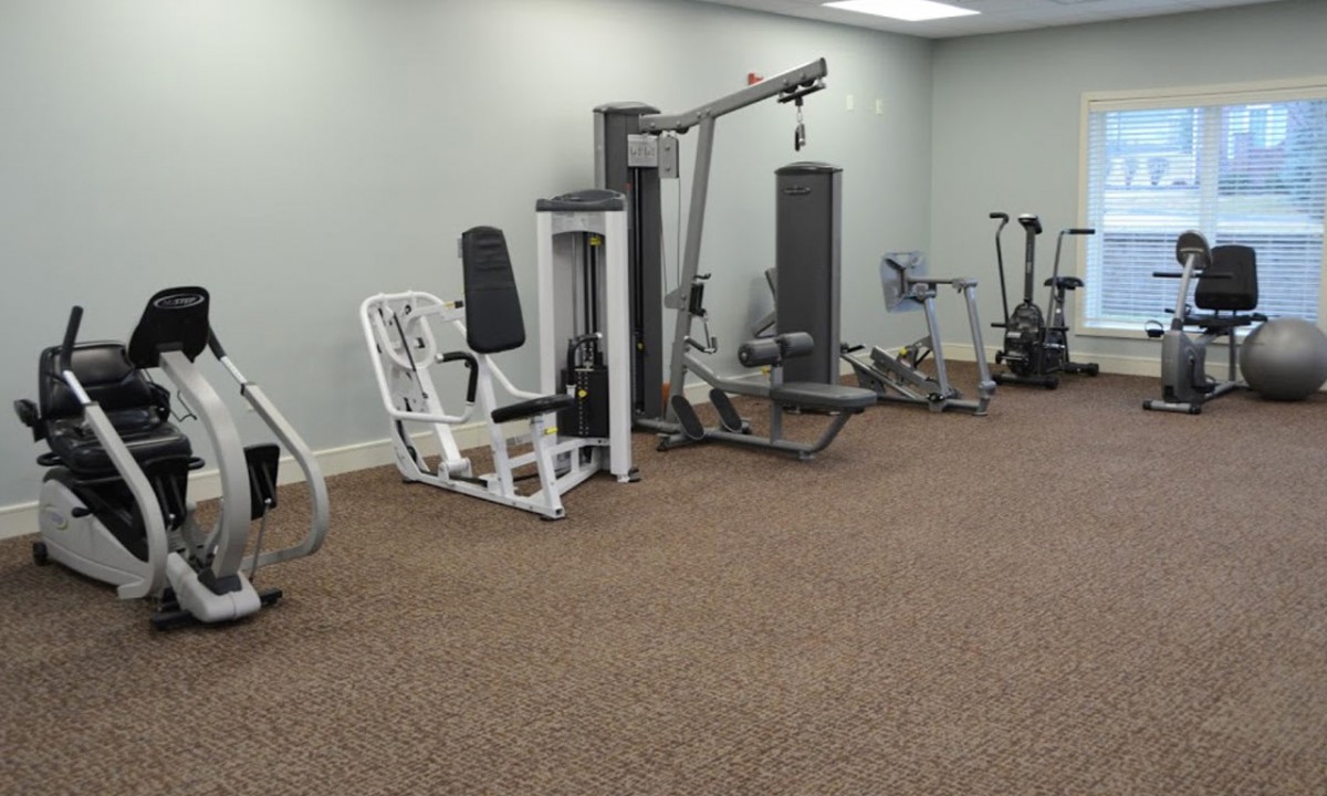 A gym with various exercise machines and equipment in an indoor setting.