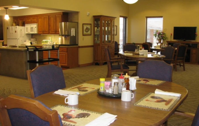 A cozy dining area with a table set for breakfast and an adjacent kitchen.