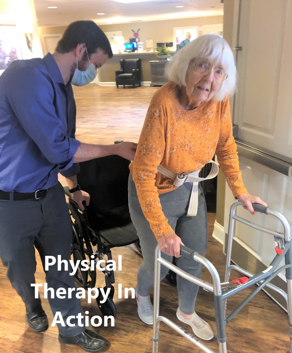 An elderly woman receives assistance from a healthcare worker during physical therapy with a walker.