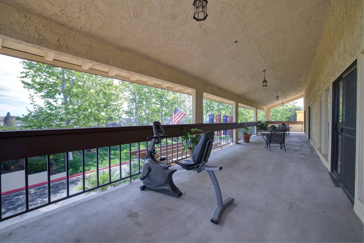 A scenic porch with an exercise bike and outdoor seating.