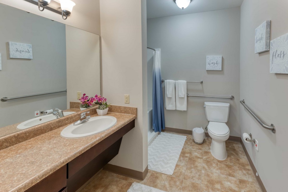 A clean and well-organized bathroom featuring a sink, toilet, and shower area with neatly arranged towels.