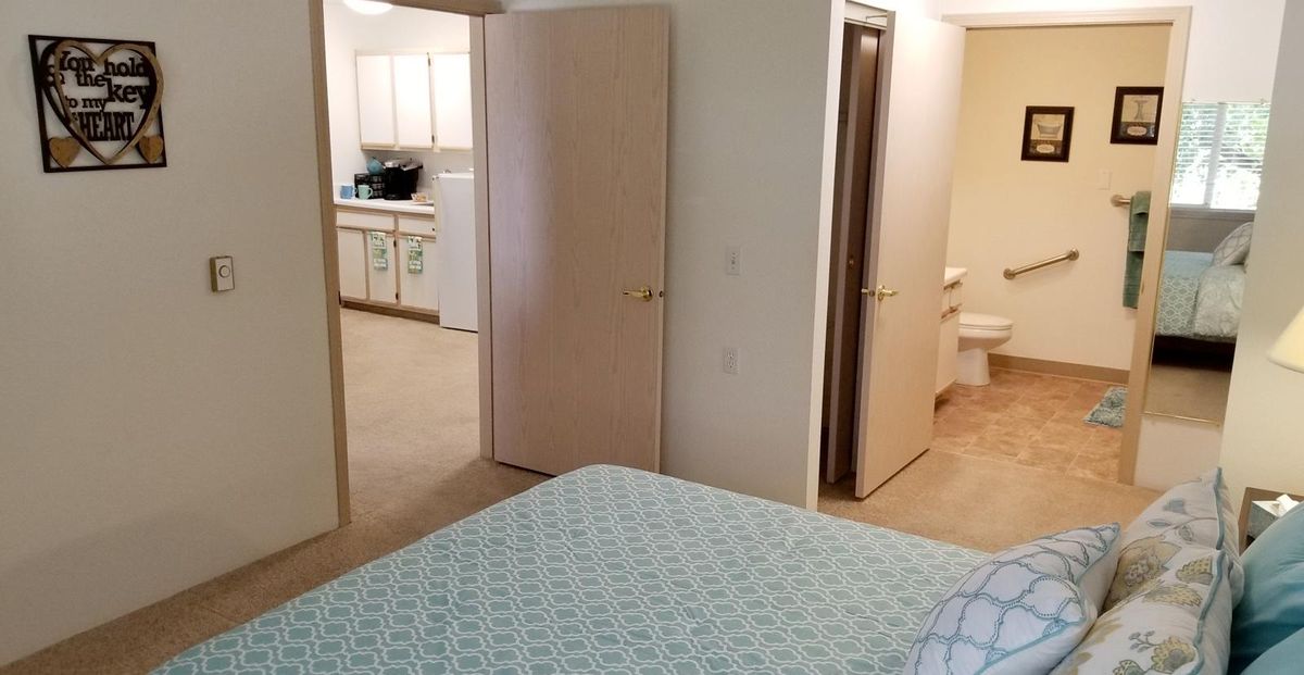 A cozy bedroom with a view into the adjoining kitchen and bathroom.