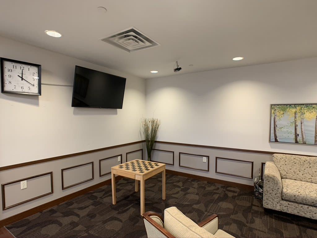 A modern waiting room with a television, seating, and a small table.