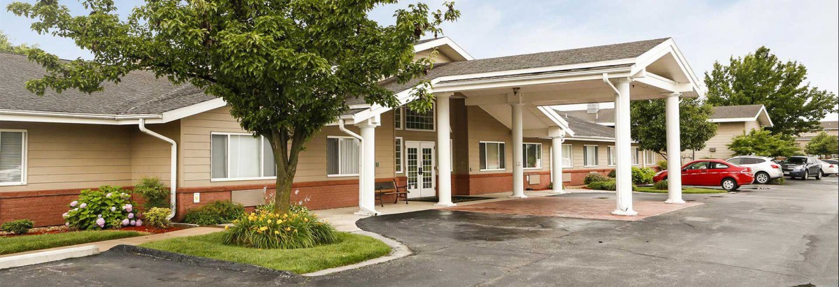 A hotel entrance with a covered driveway and surrounding greenery.