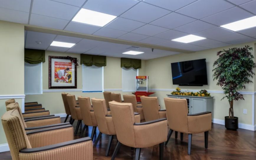 A conference room with rows of comfortable chairs facing a large television.