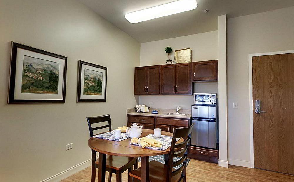 A cozy dining area with a wooden table set for a meal, adjacent to a small kitchenette.