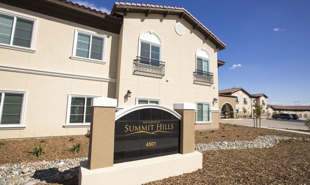 A sunny exterior view of the Summit Hills apartment building with its prominent signage.