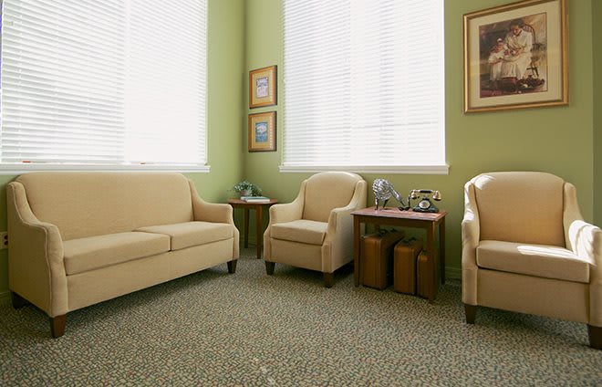 A cozy living room with beige sofas and armchairs, complemented by green walls and decorative artwork.