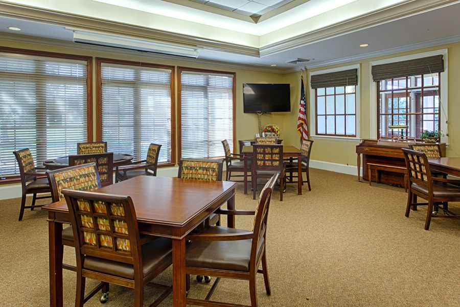 A well-appointed meeting room with wooden tables and chairs, featuring large windows and a wall-mounted television.