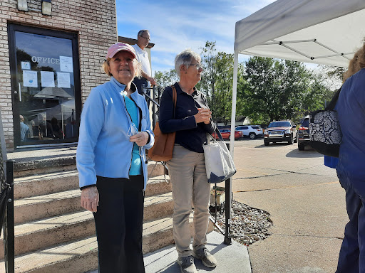 Two individuals standing outside at an event, enjoying a sunny day.
