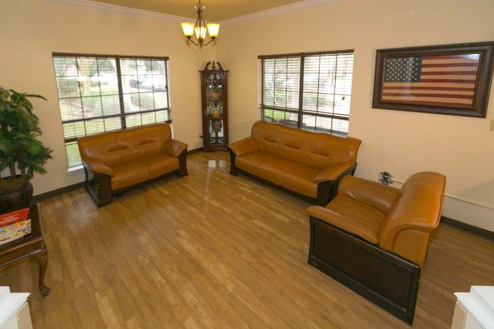 A well-lit living room with brown sofas, a coffee table, and wooden flooring.