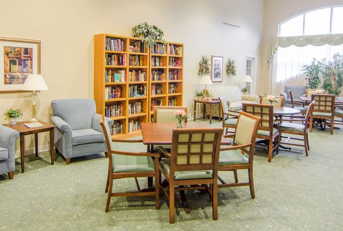 A cozy reading area with bookshelves, chairs, and tables.