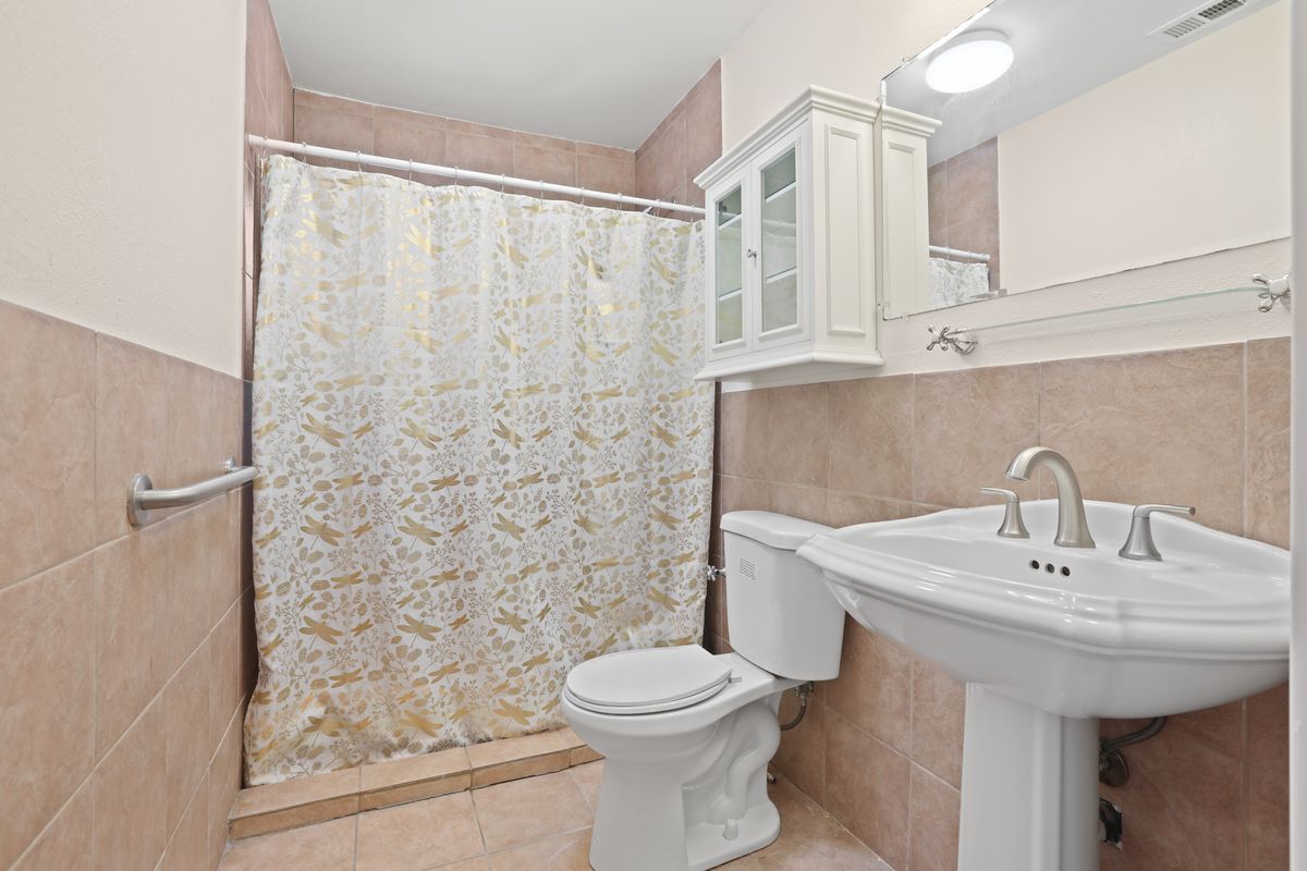 A clean and modern bathroom with a shower curtain, toilet, sink, and cabinet.