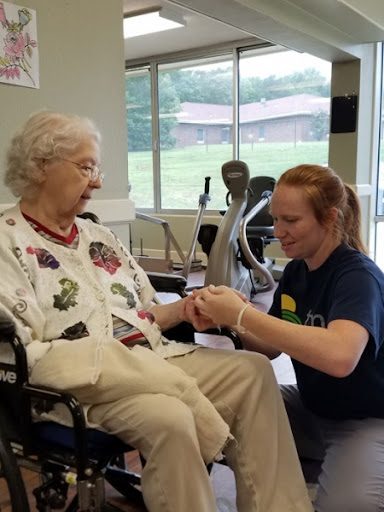 A caregiver assists an elderly individual in a rehabilitation setting.