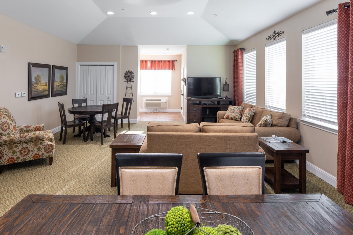 A spacious living room with an open floor plan, featuring a cozy sofa set and a dining area.
