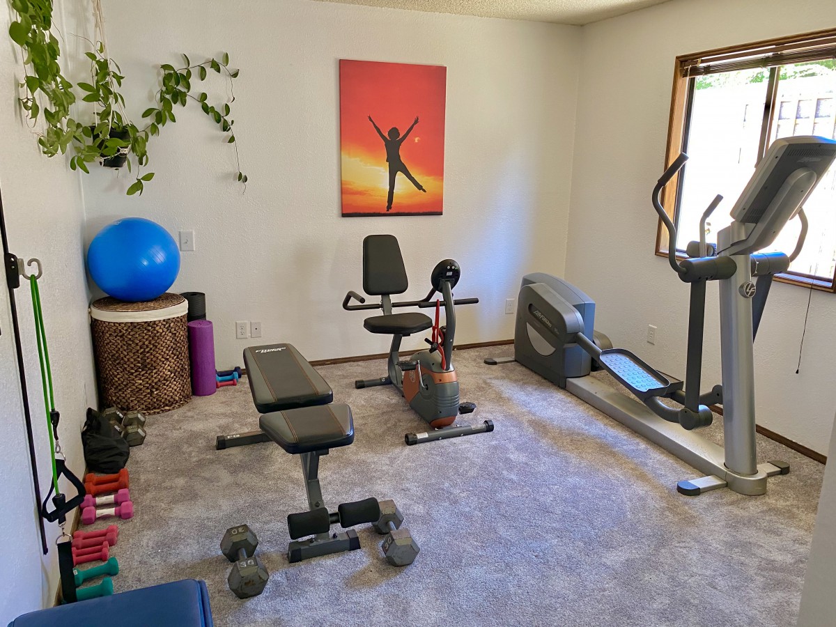 A well-equipped home gym with various exercise machines and weights.