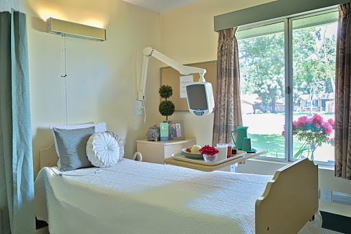 A well-lit hospital room featuring a bed, medical equipment, and a view of the outdoors.