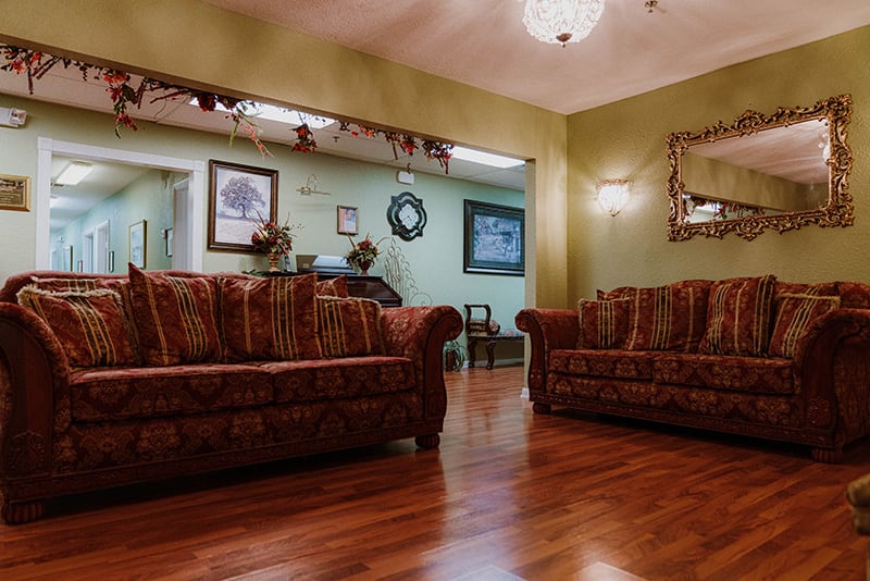 A cozy living room with patterned sofas and wood flooring.