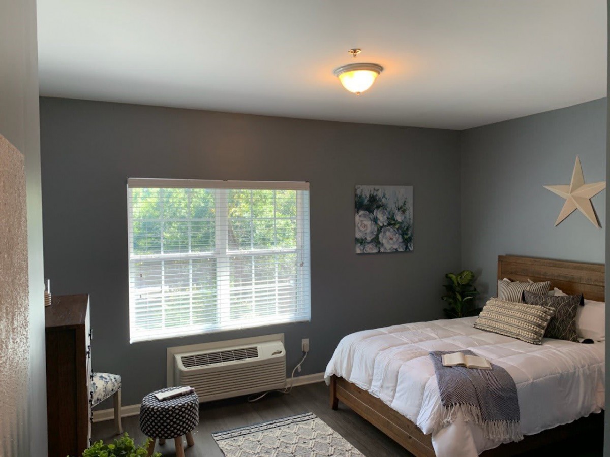 A cozy bedroom with modern decor, featuring a large window that lets in natural light.