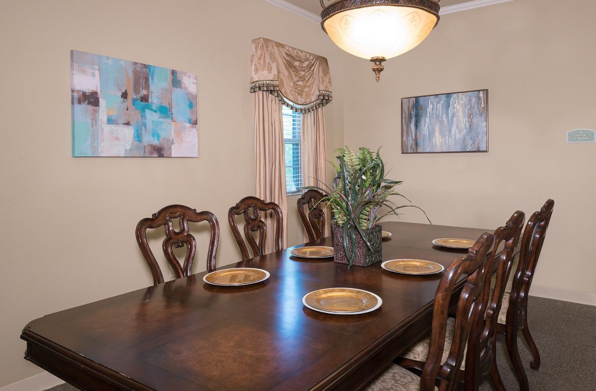 A classic dining room setup with a wooden table and chairs, decorated with plates, artwork on the walls, and illuminated by a chandelier.