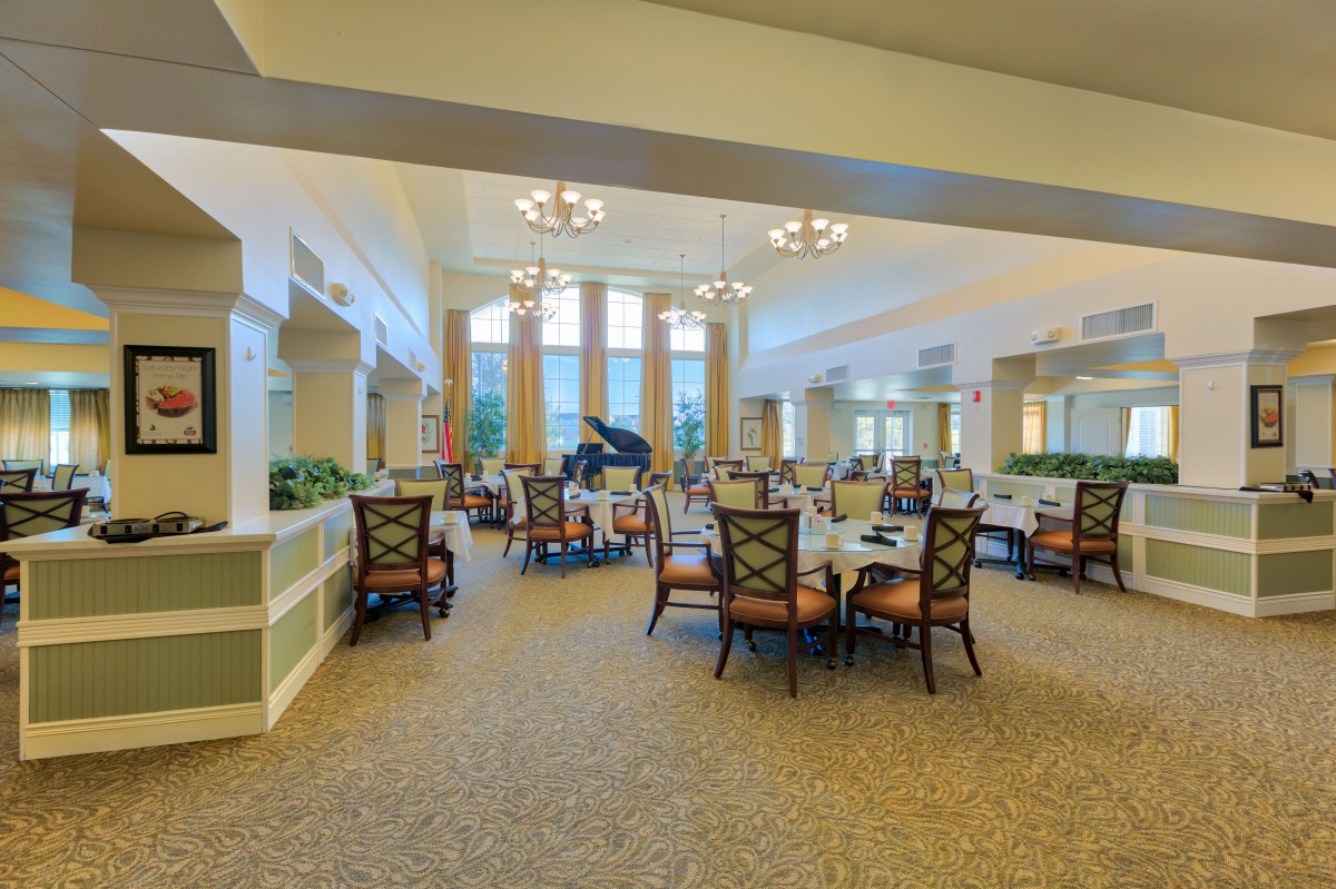 A spacious dining area with elegant furniture, featuring a grand piano and large windows.